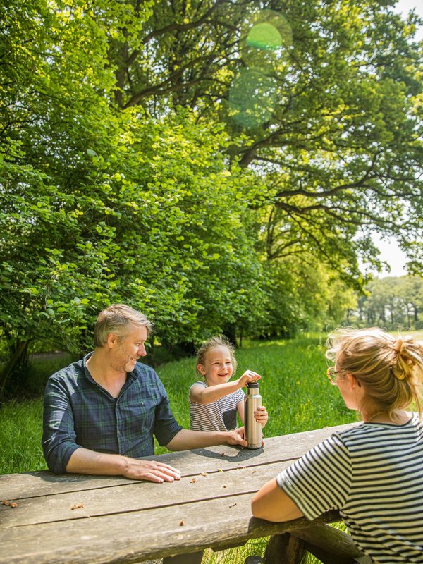 Koppel en kind aan een picknickbank aan de Drongengoedhoeve