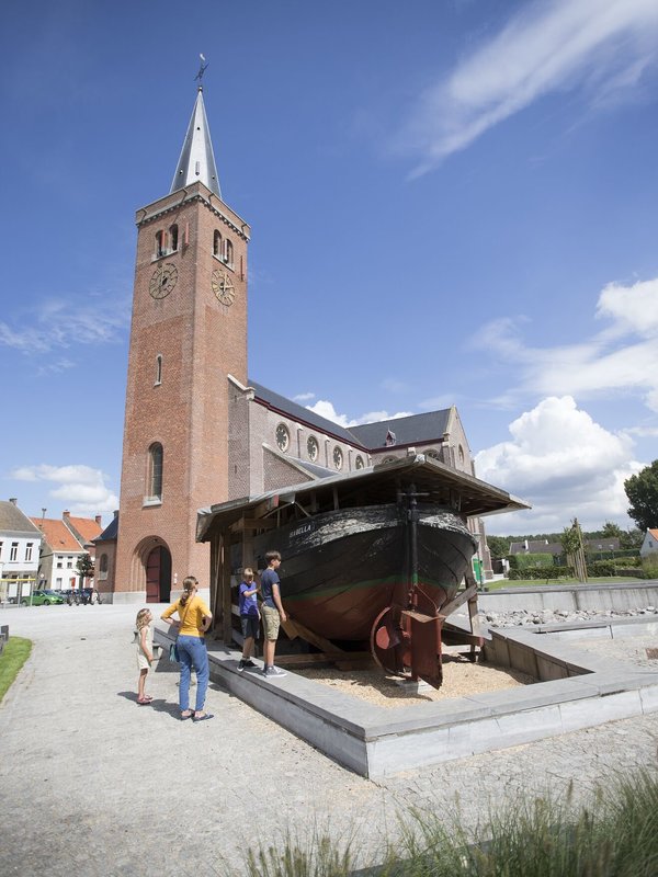 Een gezin aan de kerk van Boekhoute, met de boot met de letter BOU, het kenmerk van de Boekhoutse haven